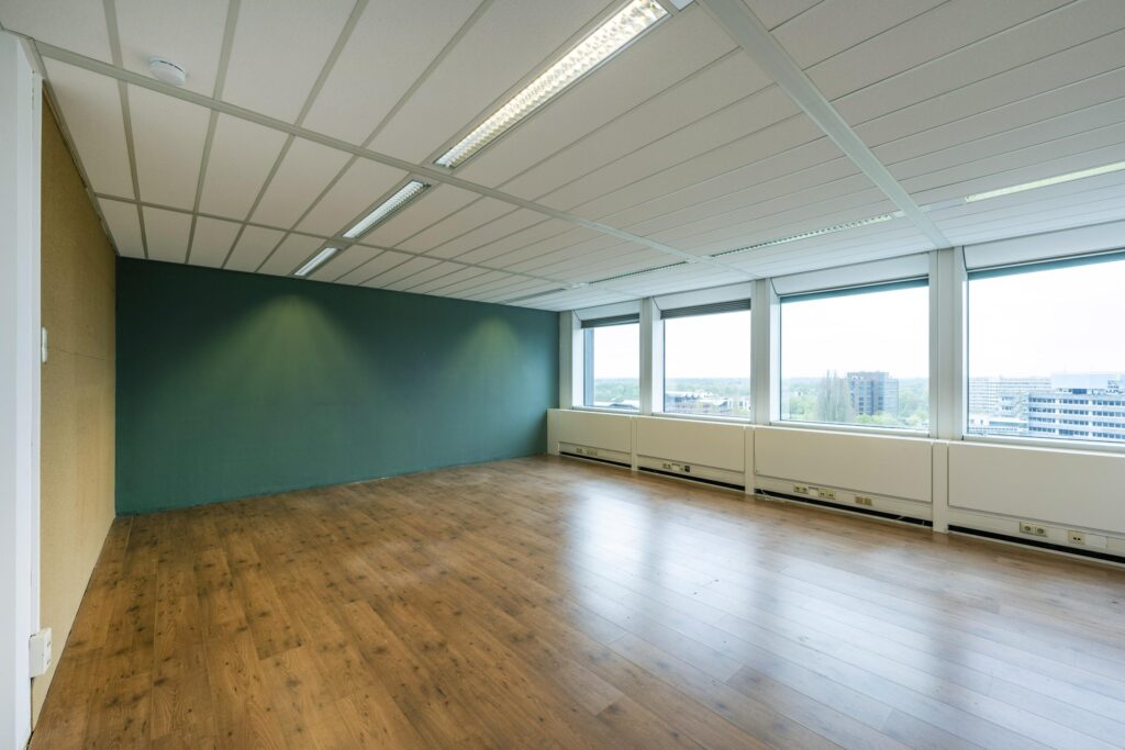 Bright, unfurnished office space with large windows and wood-style flooring at Laan van Kronenburg.